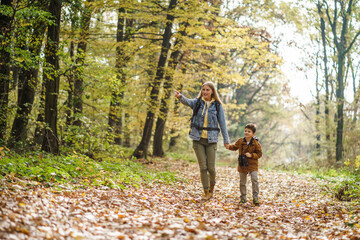 Happy mother and son are hiking in forest.