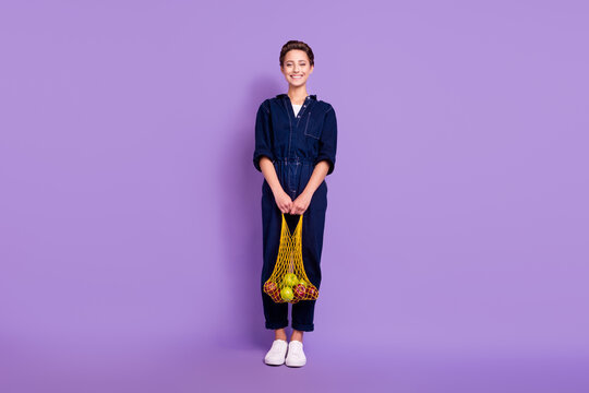 Full size photo of young smiling good mood eco-friendly girl shopping with net bag isolated on violet color background