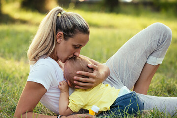 mother and her baby boy playing outdoor in public park.