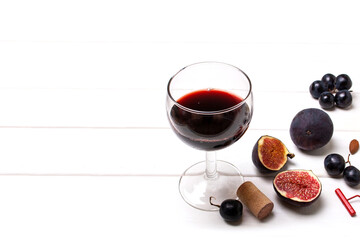 Glass with red wine, nuts, figs, grapes and empty space for text on a white wooden background