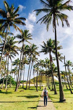 Vacation and travel concept. Happy hipster gitl walking bitween palm trees on Anakena beach, Easter Island