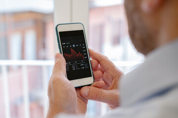 Stock market investor hands holding a phone investment app index growth chart, private banking, private investment
