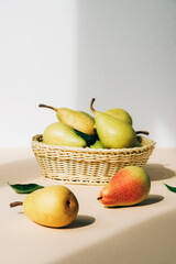 Fresh ripe pears in the basket on beige table. Healthy vegan food. Close up