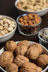 Assortment of nuts in different bowls: almond, walnut, peanut, pistachio and sunflower seed
