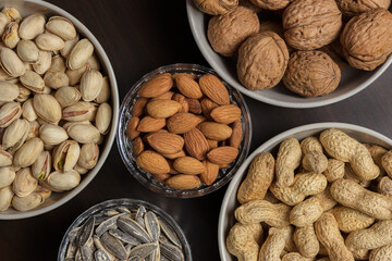 Assortment of nuts in different bowls: almond, walnut, peanut, pistachio and sunflower seed