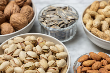 Assortment of nuts in different bowls: almond, walnut, peanut, pistachio and sunflower seed