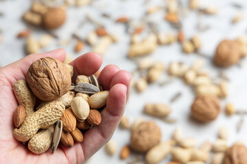 Hand holding mixed nuts: almond, walnut, peanut, pistachio and sunflower seed