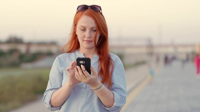 a red-haired woman with a phone at sunset, a young girl uses a smartphone to communicate