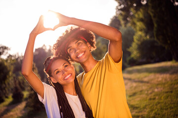 Photo portrait young couple walking together in summer green park hugging showing heart gesture