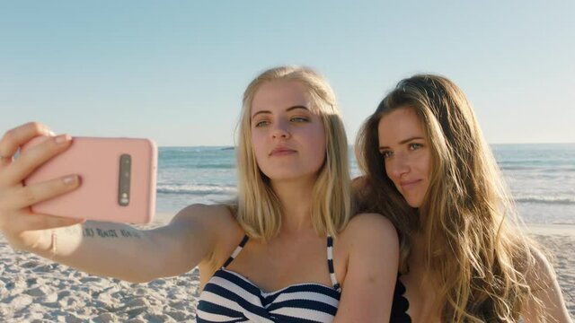 girl friends taking selfie photos using smartphone on beach having fun sharing summer vacation enjoying summertime by the sea