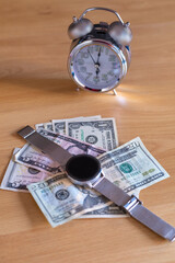 dollar money placed on a table with an analog clock and a digital clock