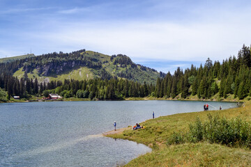 Swiss countryside. Small lake with people in the mountains in summer. Swiss Alps.