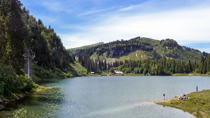 Swiss countryside. Small lake with people in the mountains in summer. Swiss Alps.