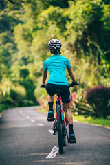 Woman cycling on tropical park trail in summer