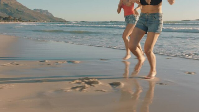 girl friends running on beach into sea splashing in water having fun playing game teenage girls enjoying warm summer day on vacation