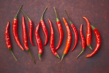 Fresh red hot chili peppers in the centre of reddish copper  metal background, top view, copy space, flat lay.