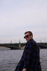 Fototapeta premium Young man walking on the embankment of Saint-Petersburg's river
