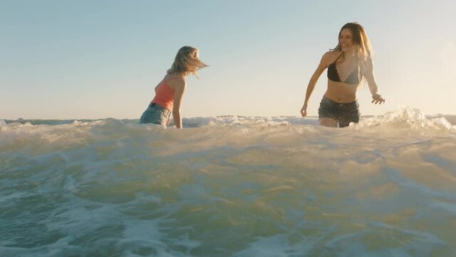best friends on beach having fun splashing in sea water teenage girls enjoying playful game on warm summer day