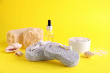 Pumice stones, cosmetic products and seashells on yellow background