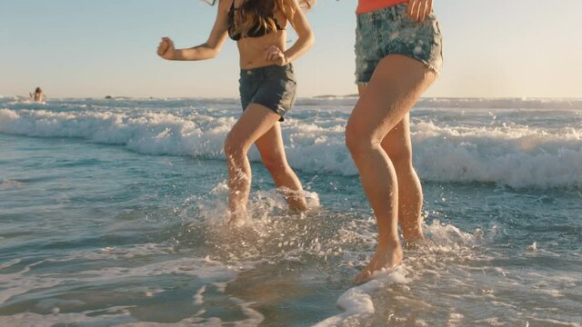 best friends on beach having fun splashing in sea water teenage girls enjoying playful game on warm summer day