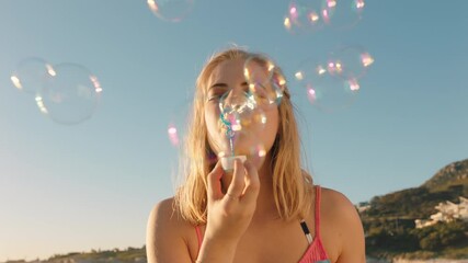 beautiful woman blowing bubbles on beach at sunset enjoying summer having fun on vacation by the sea