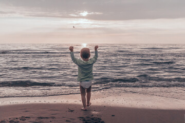 Toddler boy playing by the sea at sunset. Vacation and lifestyle concept.