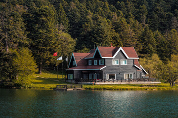 Fototapeta na wymiar Beautiful scenery of wooden lake house inside the Abant Golcuk National Park in Bolu, Turkey. Golcuk Park popular touristic place with its beautiful environment. 