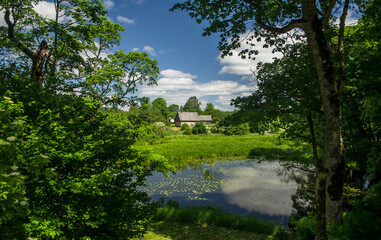 Pond in the summer with house and reflections, Edole, Latvia.