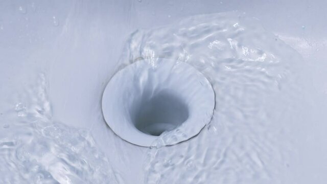 Water drains into the hole in the sink. Slow motion.