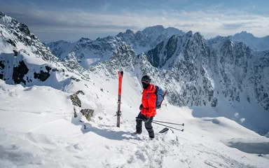 Fotobehang A skier is walking up the hill. Skitouring in Alps. Sunny weather. Hiking, adventure tourism, travel. Mountaineer backcountry ski walking in the mountains. © Pavel Kašák