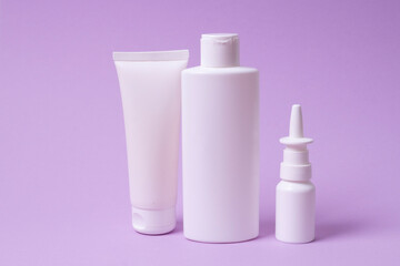 various plastic packaging for shampoo and cream on pink background