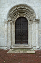 Fototapeta na wymiar Metal doors of the Dmitrievsky Cathedral. White stone building, historical monument.