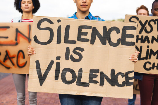 Mixed race woman holding placard saying silence is violence at protest march