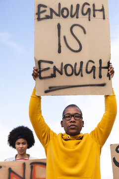 African american man holding placard saying enough is enough at protest march