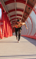 Chica haciendo técnica de arranque de atletismo en un puente rojo.