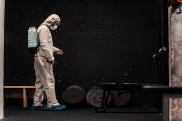 In the preventively isolated gym, a person in a special protective suit refreshes and cleans the...