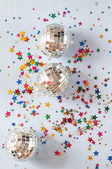 Disco ball on blue background with multicolored stars confetti 
