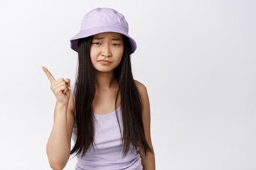 Young asian woman give warning, shaking finger and looking disappointed, scolding someone, standing over white background