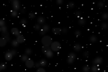 Dust particles in motion out of focus on a black background