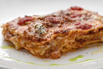 Take Out Creamy Lasagna with fresh mozzarella and tomatoes on white plate macro close up