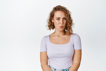 Image of blond girl cringe, looking with aversion and pity at something, grimacing from bad scene, watching something embarrassing, white background