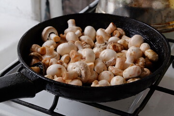 champignons are fried in a black pan close up