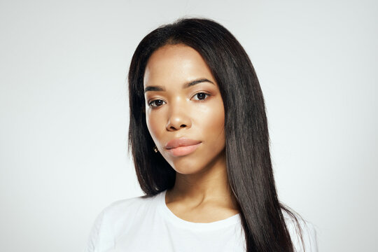 attractive woman of african appearance in a white t-shirt straightens her hair earrings