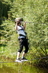 Overcoming a water obstacle. A pre-teen girl (eleven years old) overcomes a water obstacle with the help of climbing equipment. Summer time. Outdoor