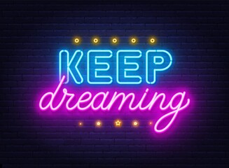 Keep Dreaming neon lettering on brick wall background.