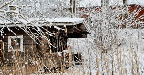 Old log sauna by the lake in winter