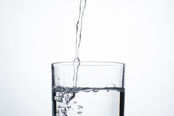 Jet of water or alcohol is pouring into a glass with splashes and bubbles, copy space