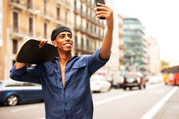 African man with skateboard. Young handsome man taking selfie photo outdoors