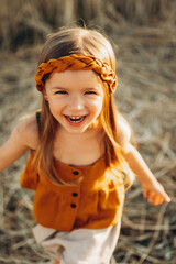 Very happy, smiling and positive little girl posing for a photo on a walk in the field