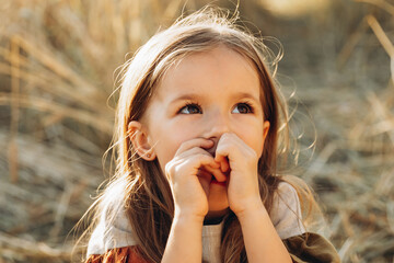 Very happy, smiling and positive little girl posing for a photo on a walk in the field